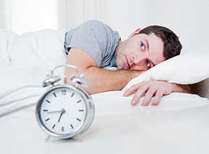 man laying awake in bed with clock, Skokie, IL sleep dentistry sleep apnea